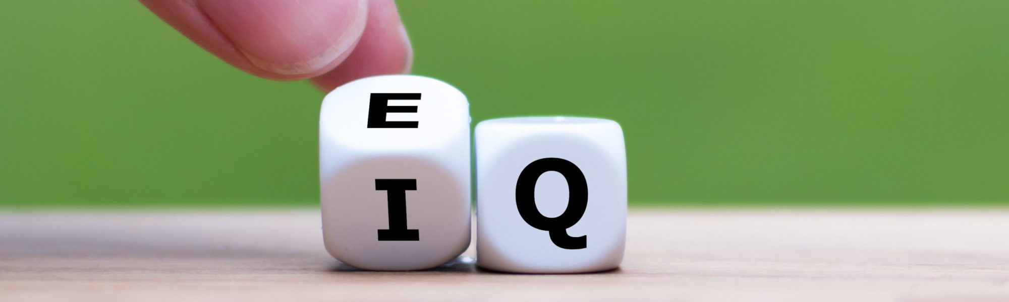 Hand turns a dice and changes the expression “IQ” (Intelligence Quotient) to “EQ” (Emotional Intelligence/Quotient). Hand turns a dice and changes the expression "IQ" (Intelligence Quotient) to "EQ" (Emotional Intelligence/Quotient).